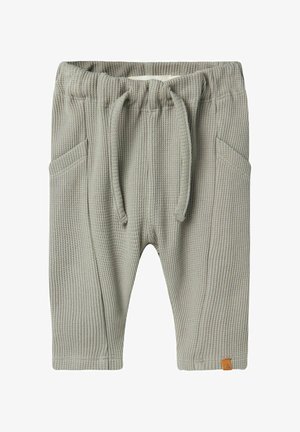 Grey knit pants with a textured waffle pattern, elastic waistband, drawstring, two side pockets, and a small logo tag near the hem.