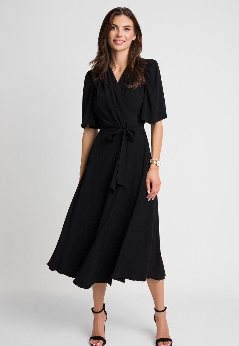 Czarna sukienka o kroju kopertowym z krótkimi, bufiastymi rękawami, talią podkreśloną paskiem oraz zwiewnym dołem, który sięga poniżej kolan. Gładka faktura materiału, minimalistyczny design.