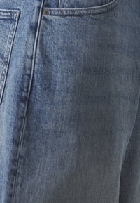 Blauwe spijkerbroek met een vervaagde wassing, voorzien van een klassiek ontwerp met vijf zakken en gestikte details langs de naden.