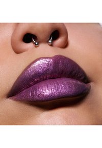 Metallic lilla læbefarve med en glossy finish, som viser glans og struktur, suppleret af en septum piercing i næsen.