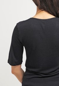 Top nero a maniche corte con scollatura tonda. Tessuto morbido, design aderente e uno stile pulito e minimalista. Nessun motivo o dettaglio visibile.