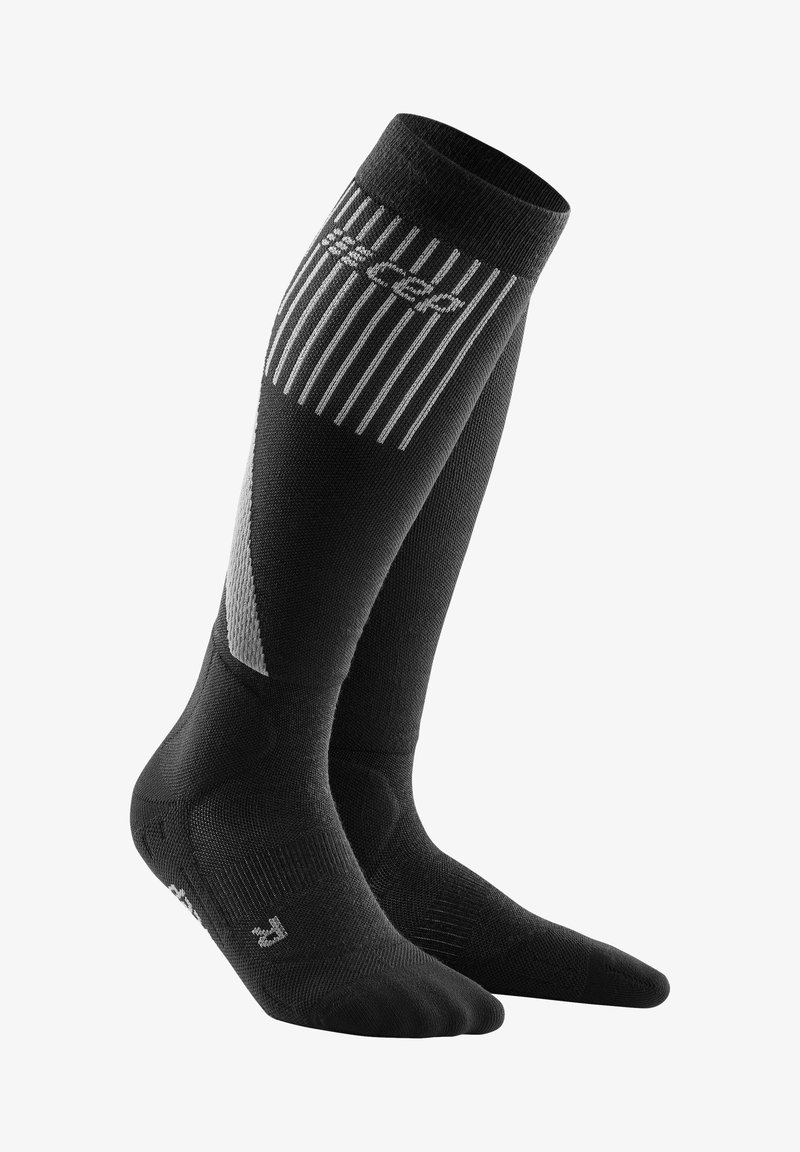 Zwart, knielange compressiekousen met een geribbeld patroon, voorzien van een reflecterend logo en diagonale paneelaccenten in grijs.