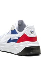 Hvide sneakers med blå og røde accenter, tekstureret sidepanel og Puma-logo på hælen. Har en glat læderoverdel og gummisål.
