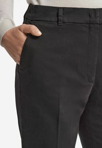 Svarta byxor med platt front, sidofickor och ett mjukt bomullsmix. Synlig midja med bälteshällor och skräddarsydd passform.