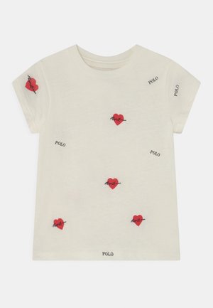 T-shirt en coton crème à manches courtes, avec une broderie de cœur rouge et le mot « POLO » imprimé en noir à plusieurs endroits.