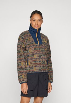 Pull multicolore avec un design à motifs comportant des formes géométriques. Col montant avec une section bleu marine et une fermeture éclair sur le devant. Deux poches latérales.