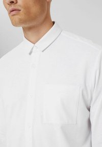 White button-up shirt with a classic collar, single chest pocket, and smooth fabric texture, featuring a slim fit design.