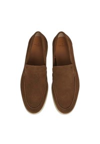 Scarpe slip-on in suede marrone con punta arrotondata e dettagli di cucitura sottili. Texture morbida, design minimalista, con una suola di colore chiaro.