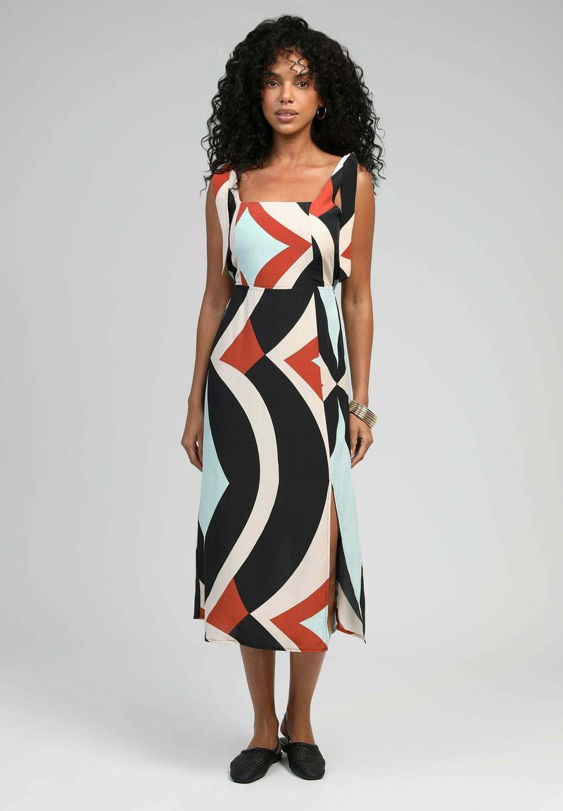 Robe maxi en tissu léger arborant un motif géométrique coloré en noir, rouge, crème et bleu clair, avec un décolleté carré et une fente sur le côté.