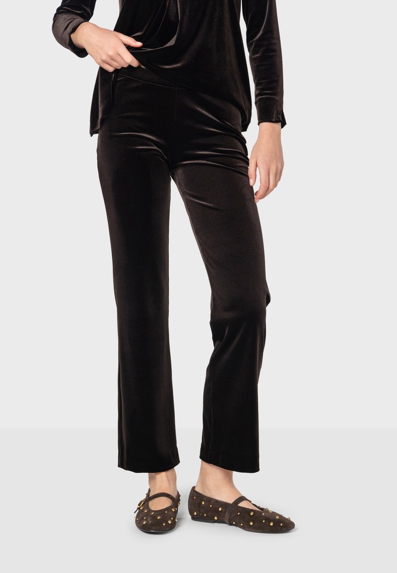 Čierne zamatové nohavice so štandardným strihom, v kombinácii s hnedými balerínami s zlatými štýlovými cvokmi. Mäkkučká textúra a elegantný silueta.