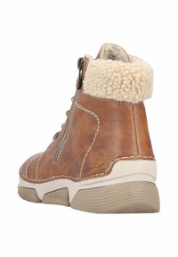 Bottines en cuir marron avec un col en peluche beige, dotées d'une fermeture éclair sur le côté et de détails de couture blanche. Semelle en caoutchouc texturé.