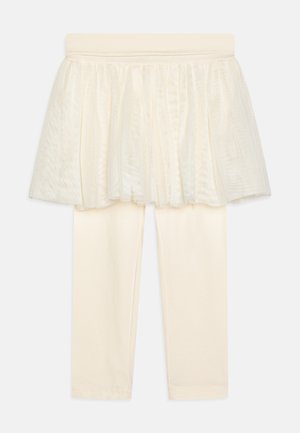 Krém színű leggings, alul tüll réteggel bevont szoknya, puha derékrésszel és sima felülettel. Az összeállítás egyszerű és elegáns.