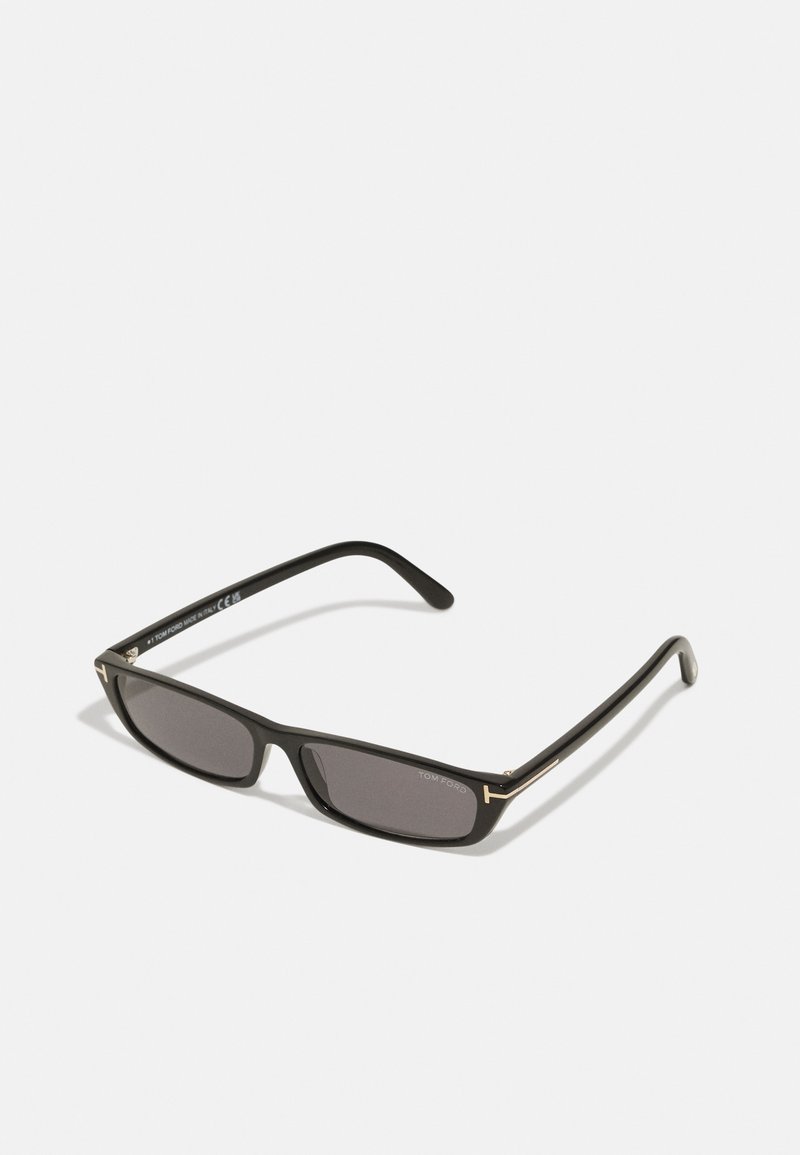 Gafas de sol rectangulares negras con lentes oscuros. Montura de plástico con acabado mate. Acentos dorados en las varillas y logotipo de marca.