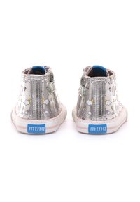 Zapatillas altas plateadas con un diseño estampado que presenta unicornios y arcoíris. Incluyen una etiqueta de marca azul y una suela a rayas rosas.