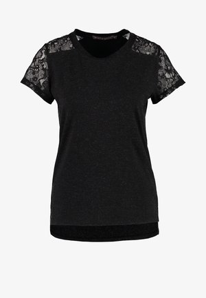 Kvinde går, iført en sort top med blonder-ærmer, hvid nederdel, sorte strømpebukser, sorte spidse sko og bærer en stor sort håndtaske.