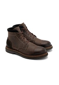 Brązowe skórzane buty z teksturowanym wykończeniem, zaokrąglonym noskiem, wyściełanym kołnierzem i kontrastującymi ciemnobrązowymi akcentami. Wcierana podeszwa zapewniająca przyczepność.