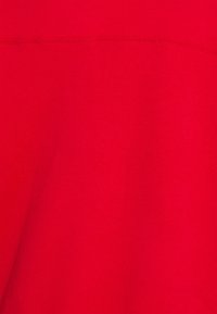 Czerwony bawełniany materiał o gładkiej fakturze; posiada subtelny detal szwu na górze. Jednolity kolor bez wzorów czy akcentów.