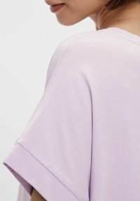 Fioletowa koszulka z krótkimi rękawami, okrągłym dekoltem i miękką, gładką teksturą. Charakteryzuje się luźnym krojem oraz starannym wykończeniem szwów.