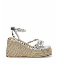 Sandalias de cuña metálicas plateadas con correas entrelazadas, plantilla de cuerda trenzada y suela texturizada. Incluye correa ajustable para el tobillo.