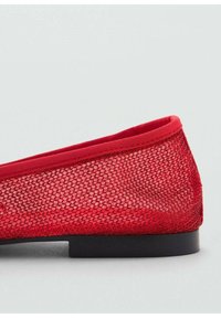 Red mesh flat shoe with a textured upper and a smooth black sole; features a rounded toe and a low, flexible heel.