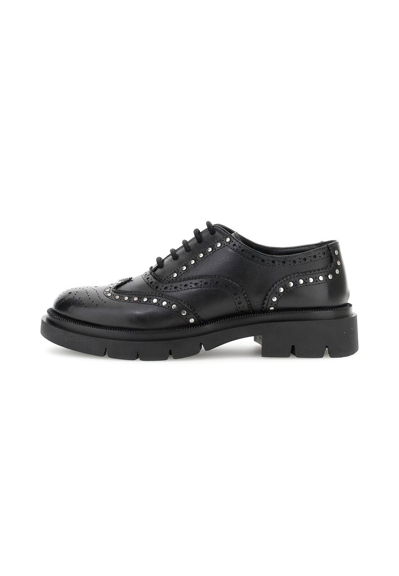 Zwarte leren oxford schoen met decoratieve perforaties en metalen studs, voorzien van een dikke zwarte zool en een traditionele vetersluiting.
