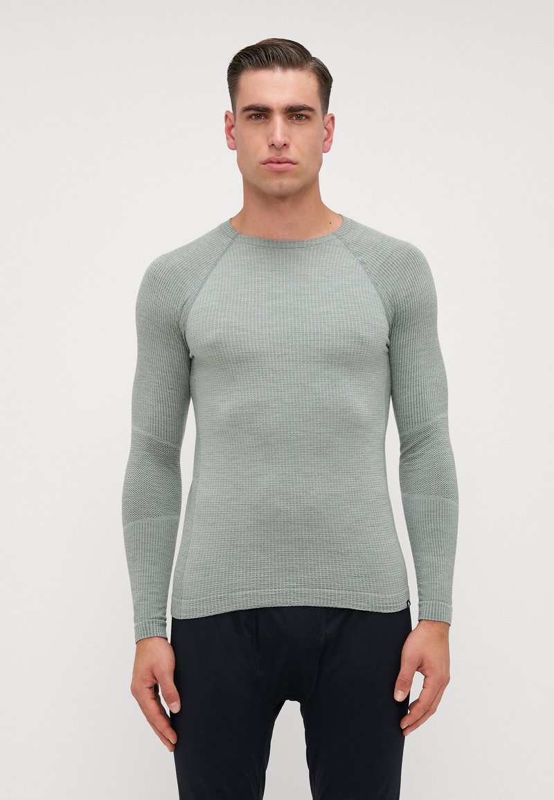 Camisa justa de manga longa em verde claro, feita de tecido de malha texturizada. Apresenta mangas raglan e um decote redondo com punhos canelados.