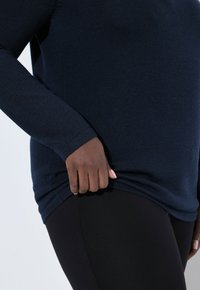 Marineblauw long-sleeve top gemaakt van zachte gebreide stof, met een slim fit, ronde halslijn en een gestructureerde afwerking, gecombineerd met zwarte leggings.