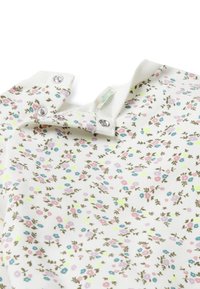 Witte katoenen shirt met een bloemenpatroon in roze, blauw en groen. Beschikt over drukknoopsluitingen bij de kraag en een zachte ribgebreide halslijn.