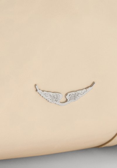 Sac en cuir beige avec un ornement en métal argenté en forme d'aile, présentant des motifs de plumes détaillés. Texture lisse au design minimaliste.