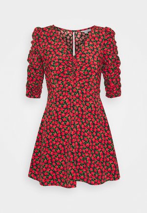 Abito corto rosso con fantasia floreale, maniche a tre quarti arricciate e scollo a V su sfondo chiaro uniforme.