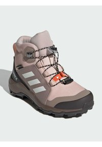 Ružičasta planinarska čizma s teksturiranim gornjim dijelom, reflektirajućim trakama, crnim vezicama i čvrstom sivom gumenu potplatom. Ima podesivi završetak na vrhu.