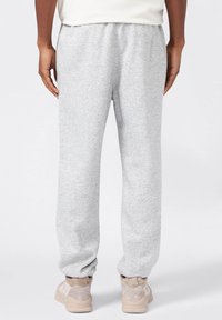 Pantaloni sportivi grigi con vita e polsini elasticizzati, realizzati in tessuto morbido. Le caratteristiche principali includono una vestibilità rilassata e una sartoria minimale.