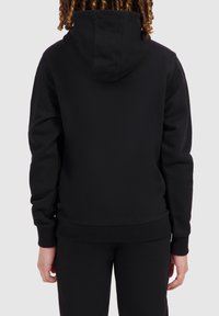 Zwarte hoodie met een capuchon en geribbelde manchetten. Soepele textuur, slim fit ontwerp en naadloze achterkant. In combinatie met bijpassende zwarte broek.