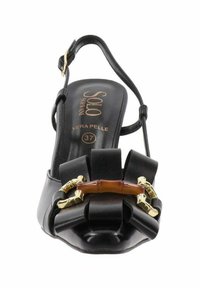 Sandalo in pelle nera con punta arrotondata, dotato di un accento a fiocco, dettagli in bambù e hardware dorato. Include una cinghia regolabile alla caviglia.