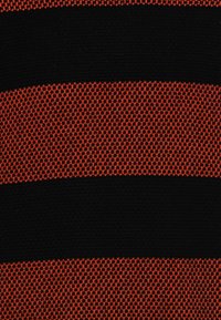 Tejido de punto con atrevidas rayas horizontales en rojo y negro. La textura parece resistente y tejida de manera apretada, con un patrón de cuadrícula pronunciado.