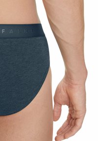 Dunkelblaue Herrenunterhosen mit einer schlichten Textur und einem weichen, breiten Bund, der das dezente Branding "FALKE" trägt. Seitenansicht, die das Bein und den Bund betont.