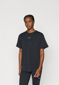 Juodas medvilninis marškinėlis su apvalia iškirpte, trumpomis rankovėmis ir baltos spalvos Nike logotipu, esančiu krūtinės centre. Lygus audinys, laisvas kirpimas.