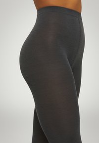 Leggings grigi scuri realizzati in materiale morbido e elastico, caratterizzati da una superficie liscia e una vita elasticizzata, progettati per comfort e vestibilità.