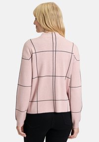 Rosa gestrickter Pullover mit schwarzem Gittermuster, hohem Kragen und abgesenkten Schultern, der eine lockere Passform sowie Rippabschlüsse am Saum und an den Bündchen aufweist.