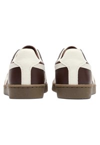 Pair of low-top brown and white sneakers shown from the back with beige soles on a white background.