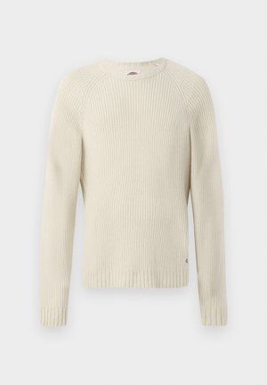Maglione di colore crema a coste con maniche lunghe, scollatura rotonda e un'etichetta con logo sul lato inferiore. Tessuto testurizzato, vestibilità standard.