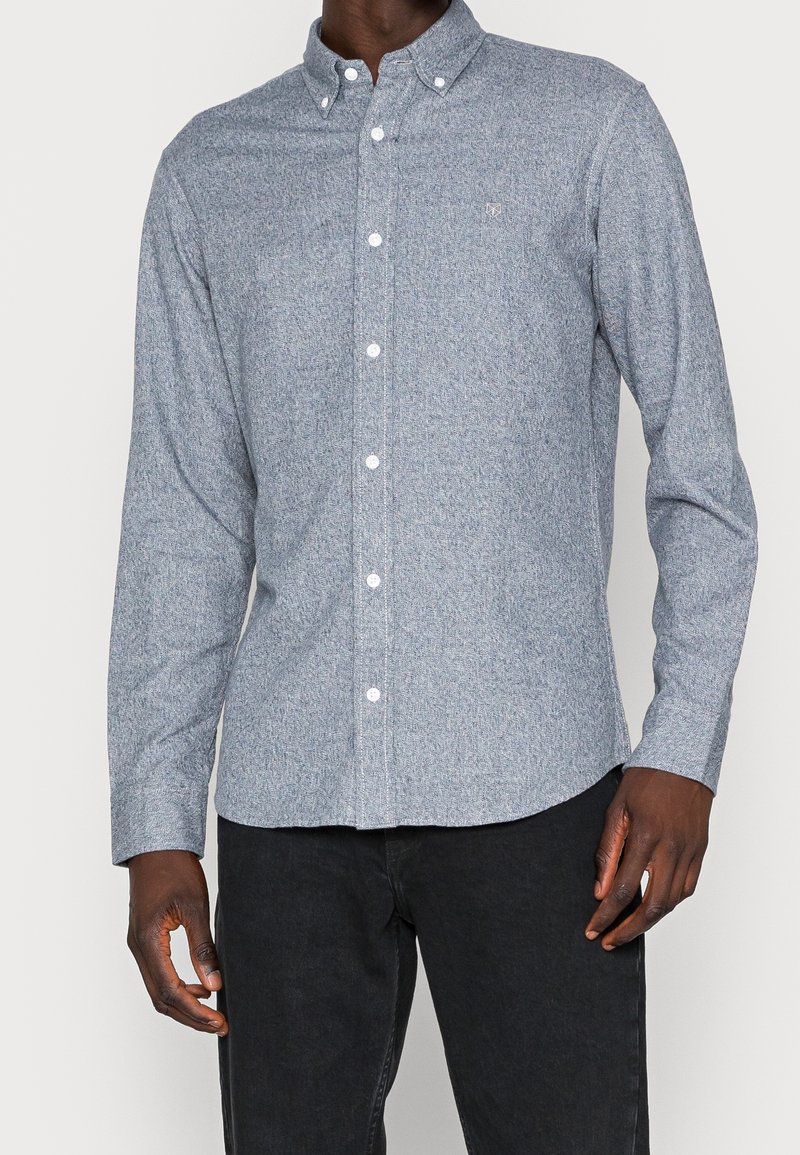 Camicia azzurro chiaro con bottoni, realizzata in tessuto intrecciato. Presenta un colletto, chiusura con bottoni, maniche lunghe e un piccolo logo tonal sul petto.