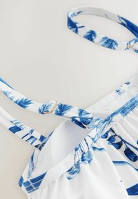 Kék és fehér bikini felső virágmintával, állítható pántokkal és ezüst színű részletekkel. Finom, rugalmas anyag.