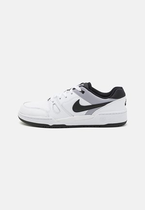 Baskets basses Nike blanches, grises et noires avec un design à lacets et un logo Nike Swoosh noir sur le côté, vues de l'extérieur.