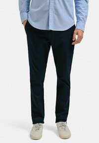 Marina chinos i bomull med rak passform. Bärs med en ljusblå skjorta med knappar och beige sneakers. Slät textur, minimal detaljering.