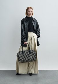 Μαύρο δερμάτινο υπερμεγέθη πουκάμισο, μαύρο ριμπ τοπ, φαρδιά μπεζ πλισέ παντελόνια και μαύρη-λευκή τσάντα με σχέδια. Ομαλή υφή, μεγάλος όγκος.