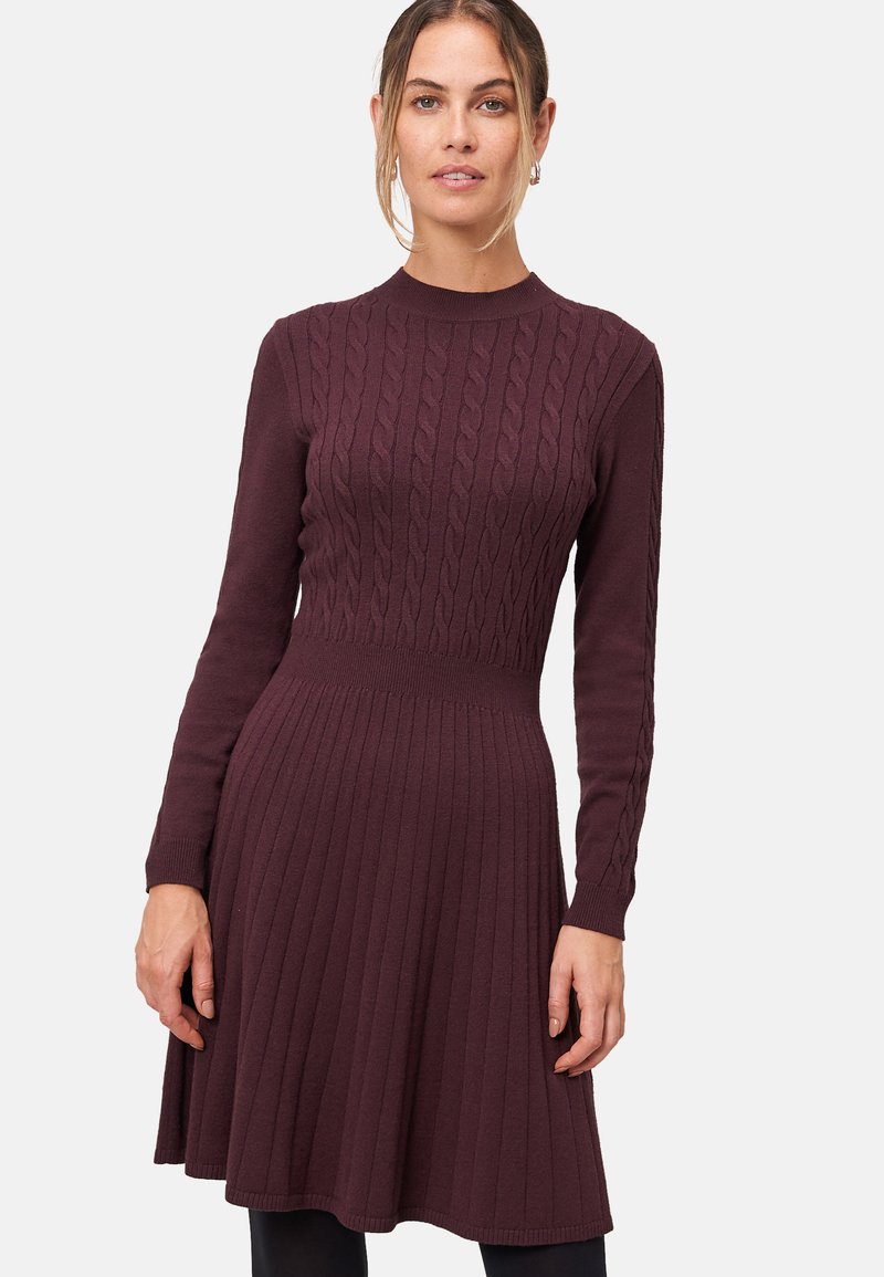 Robe tricotée dans un bourgogne profond, avec un design à côtes, des manches longues et un bodice ajusté qui se prolonge en une jupe plissée.