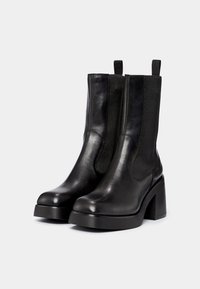 Czarne botki za kostkę wykonane z gładkiej skóry, z elastycznymi panelami po bokach, obcasem typu słupek oraz pętlami do łatwego zakładania.