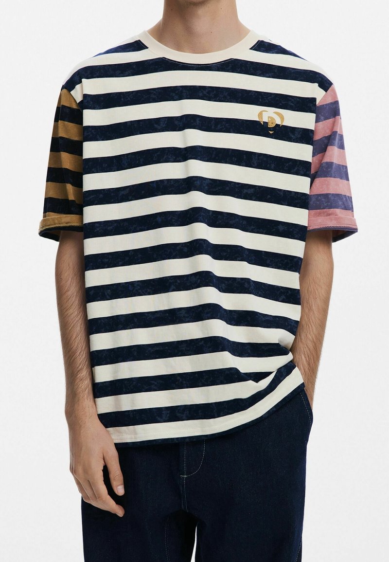 Koszulka w paski w kolorach granatu, kremowym i pastelowym; krótkie rękawy z różnymi wzorami; małe logo na lewej stronie klatki piersiowej.