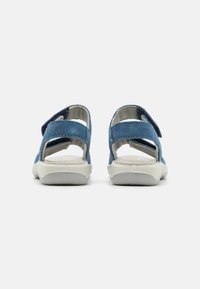 Blå semskede sandaler med justerbare borrelåsremmer, åpen bakdesign og grå gummisåler. Teksturert fotseng synlig.